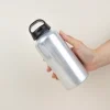 Mano sujetando una botella de agua reutilizable de aluminio reciclado