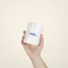 Mano mostrando una taza de cerámica blanca con puntos negros personalizada con la palabra logo en azul