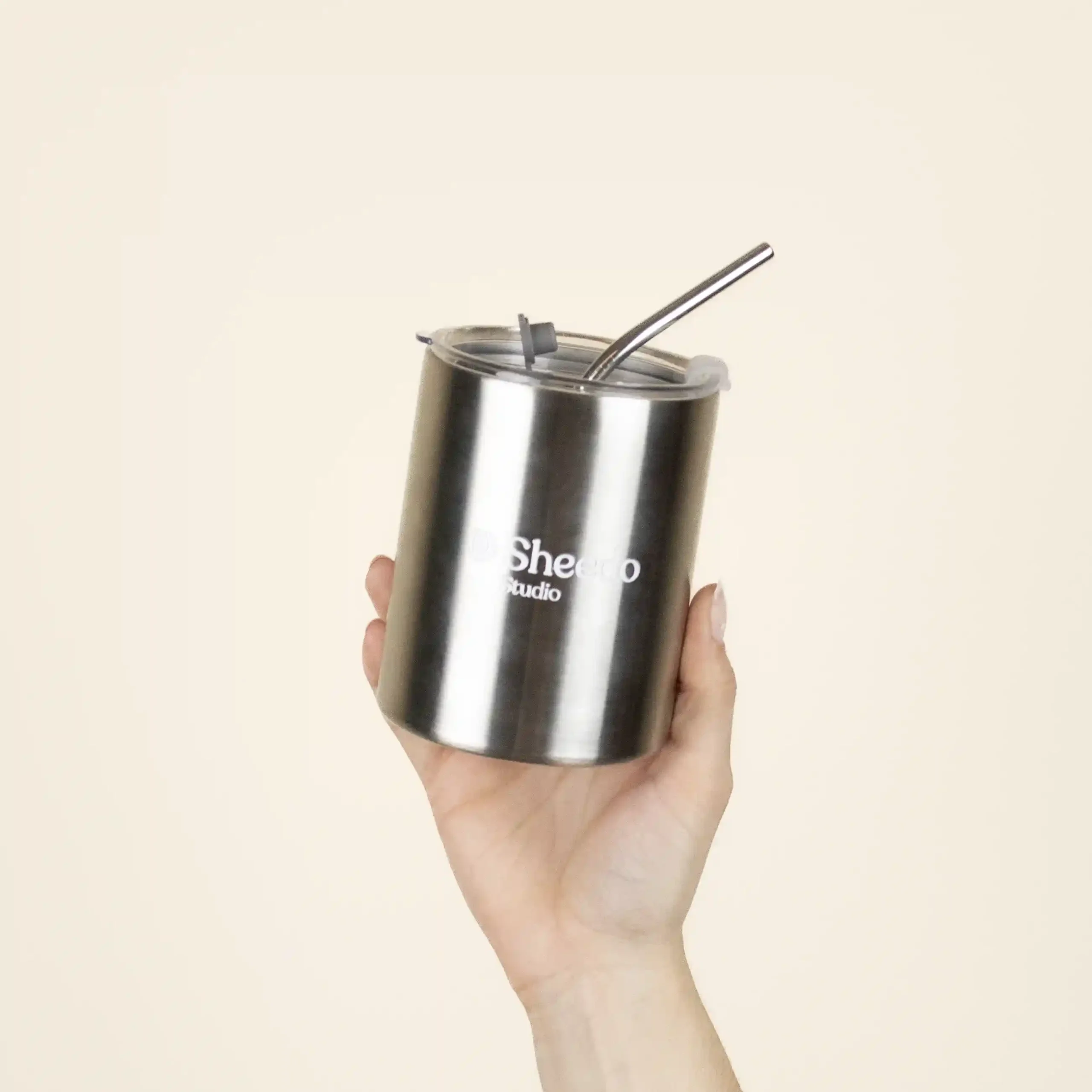 Taza take away con pajita MOON Taza take away con pajita color plateado personalizado logo blanco modelo mano fondo beige