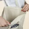Manos abriendo una bolsa de algodón personalizada con logo azul
