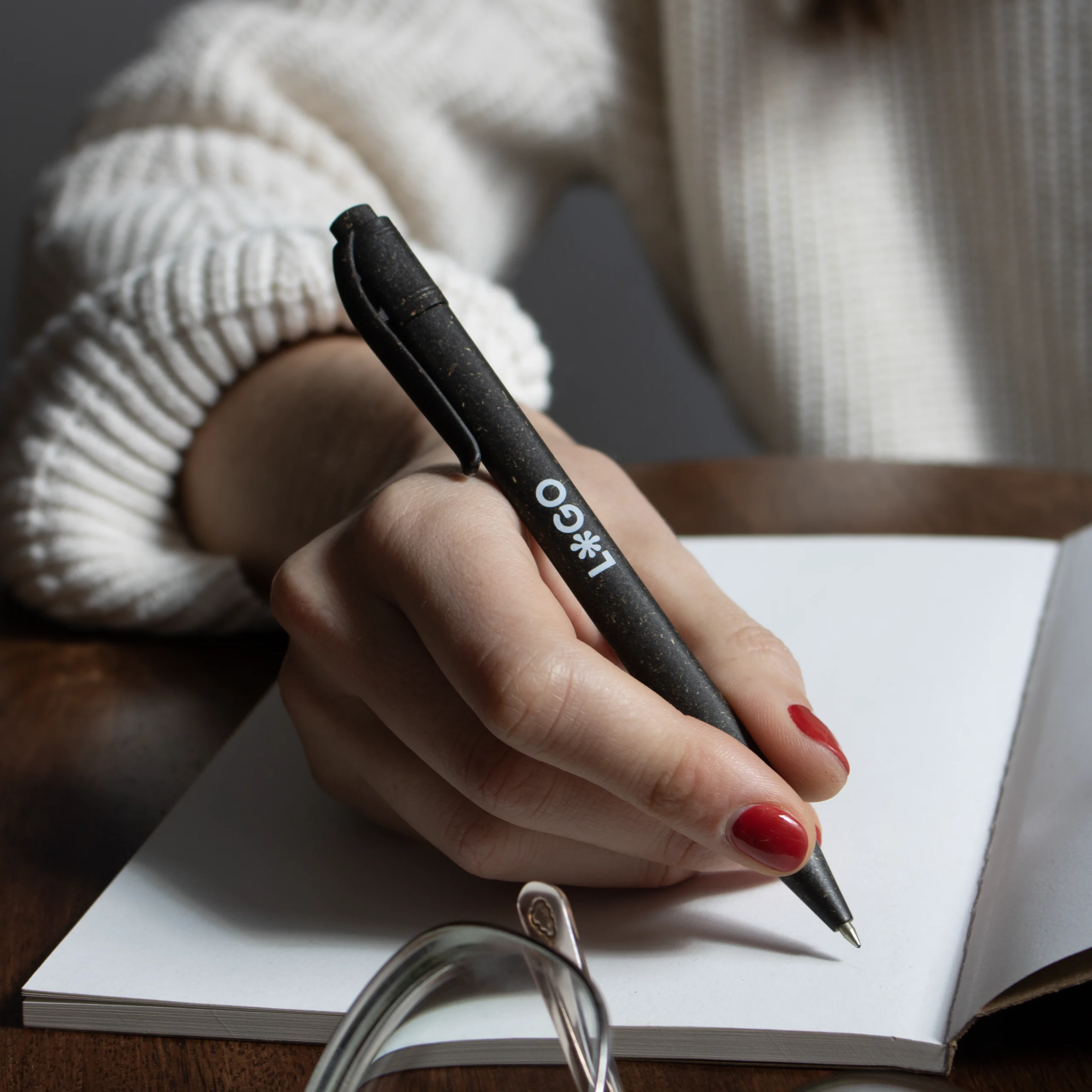 mano escribiendo en cuaderno con bolígrafo de bioplástico de césped