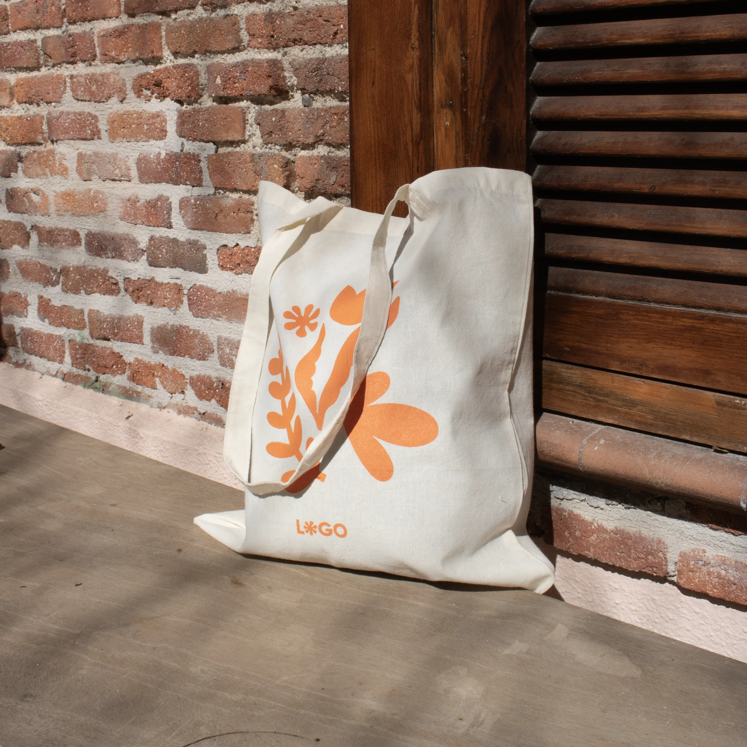 Bolsa de algodón personalizada con un diseño naranja apoyada en el suelo