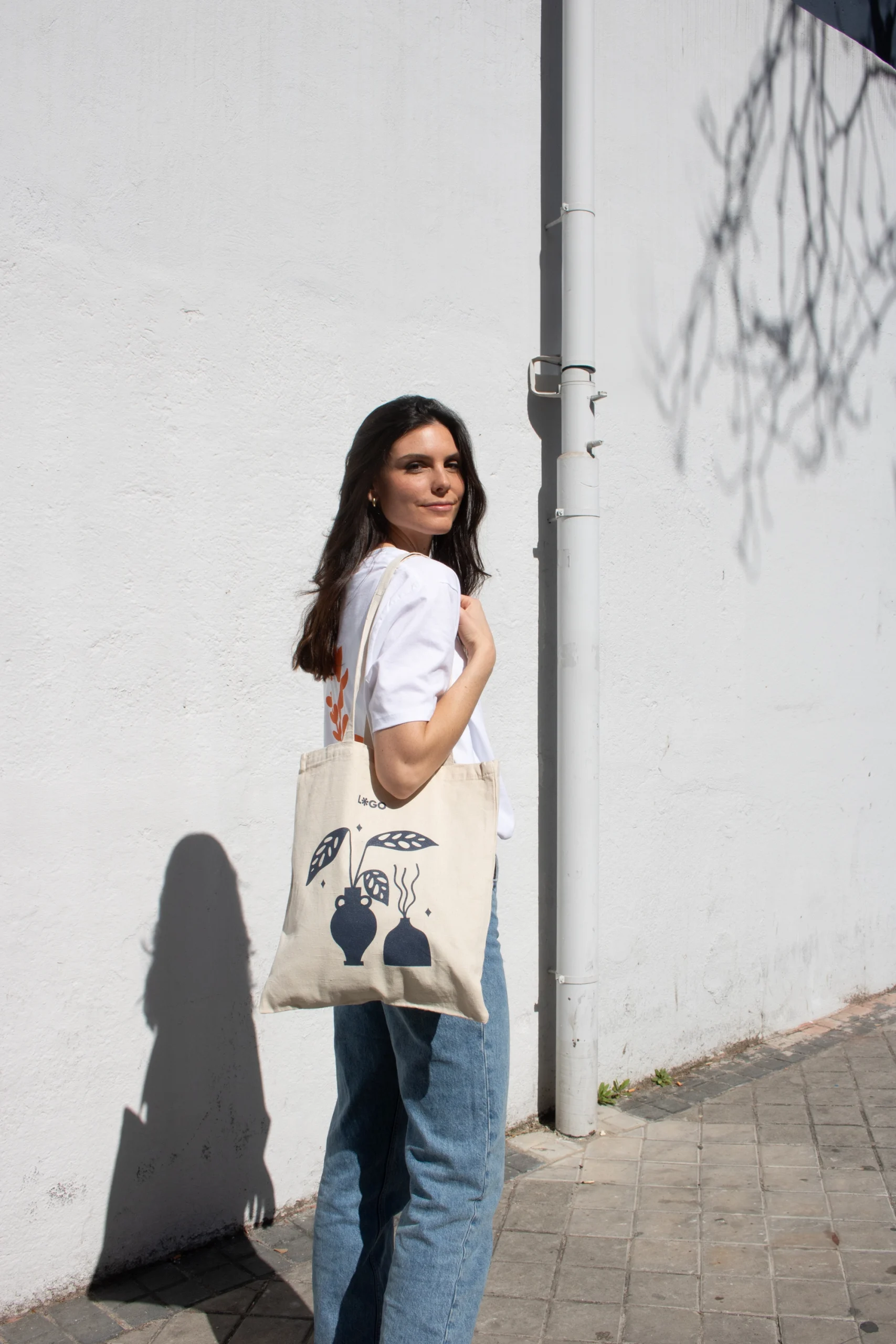 Cotton tote bag NATA 240 Chica paseando en la calle llevando una bolsa de algodón personalizada con logo azul