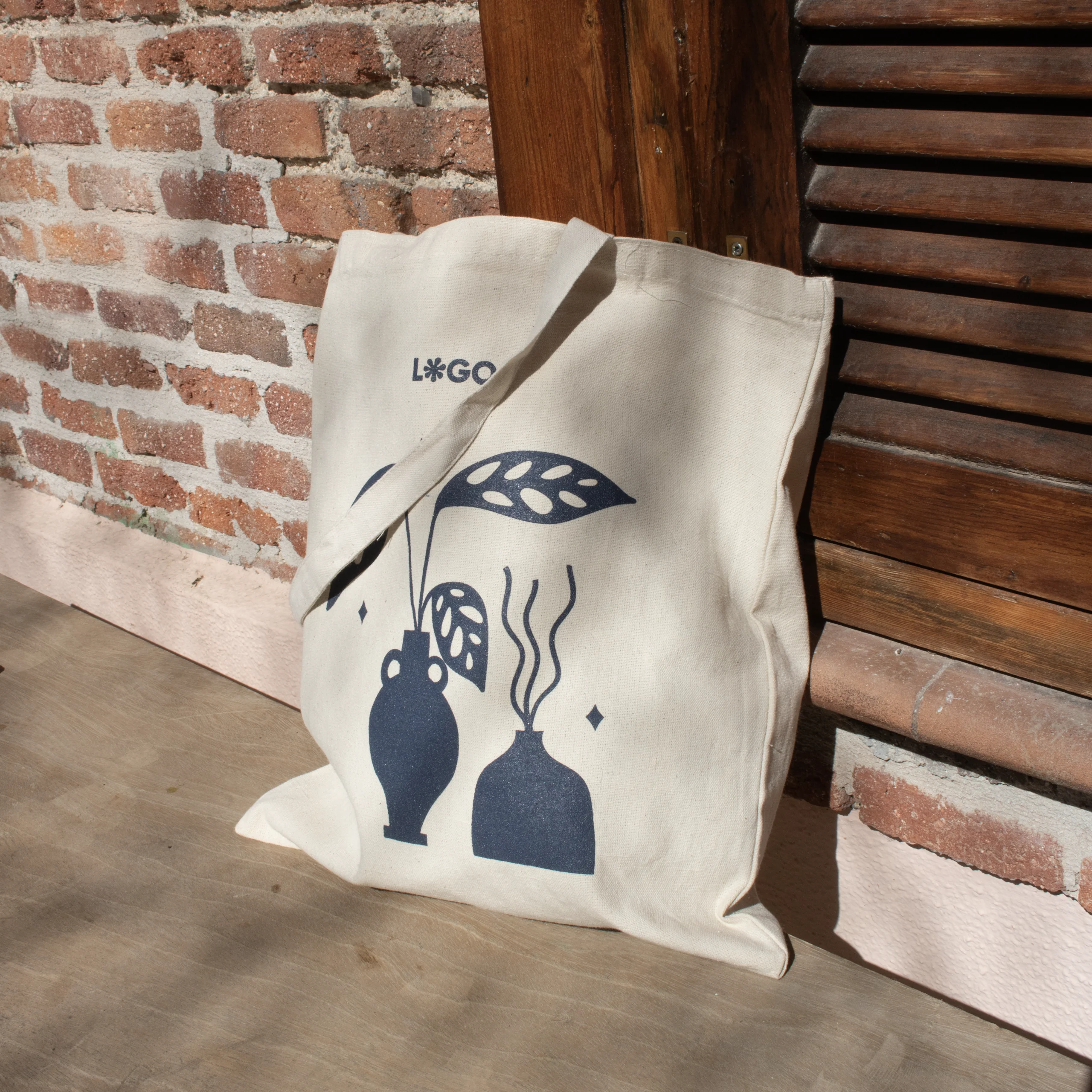 Cotton tote bag NATA 240 Bolsa de algodón personalizada con logo azul apoyada en el suelo