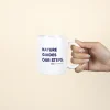 Taza Blanca personalizada con logo azul modelo mano sobre fondo beige