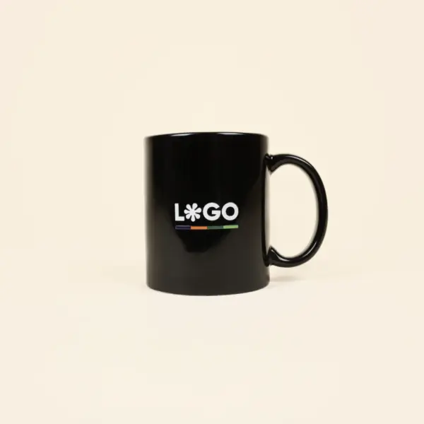 Taza negra con asa personalizada con la palabra logo en blanco fotografiada sobre un fondo beige