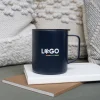 Vaso térmico con asa azul con logo blanco apoyada en cuadernos