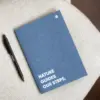 Cuaderno de grapa azul portada personalizada con texto blanco y bolígrafo