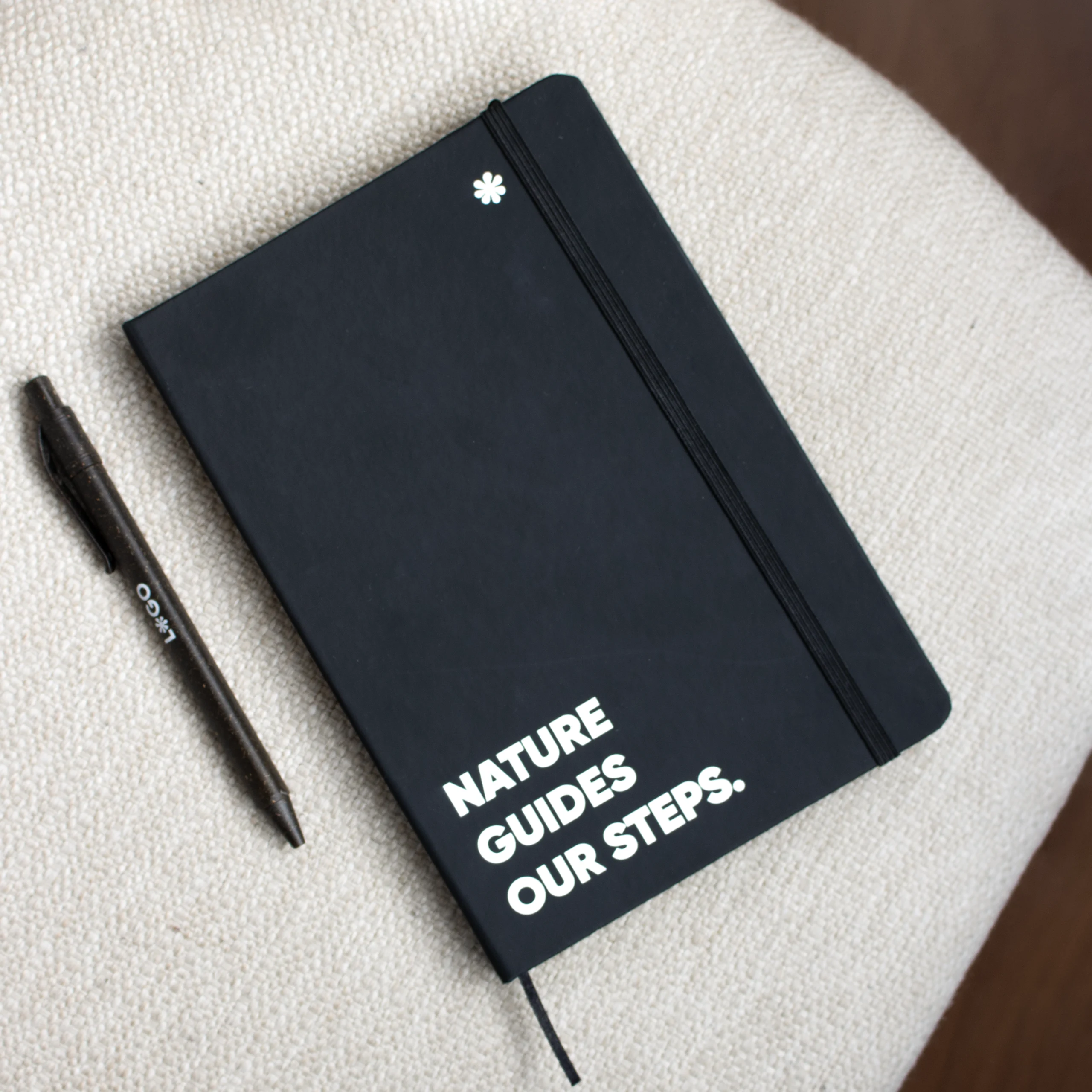 Cuaderno reciclado negro personalizado con texto blanco y bolígrafo marrón