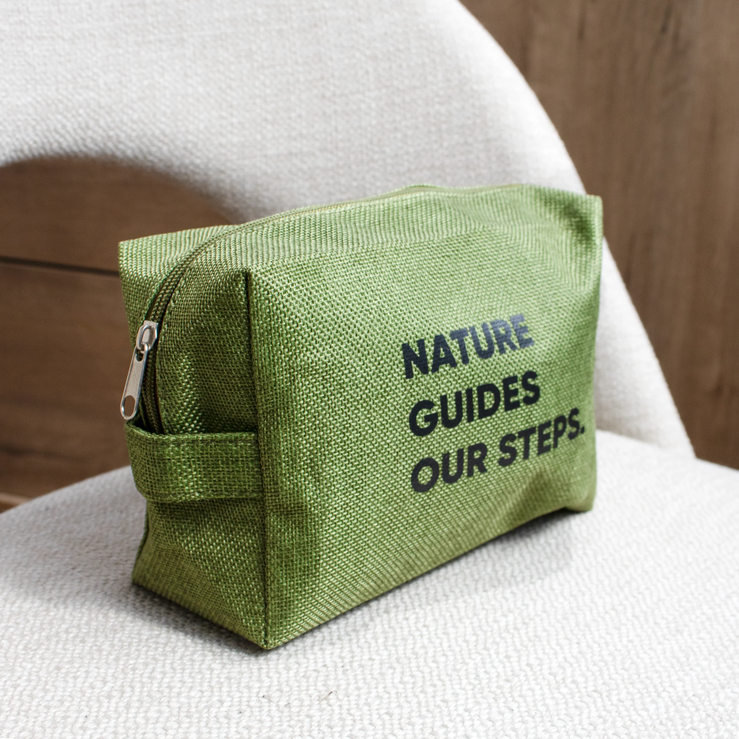 Trousse de toilette verte personnalisée avec texte noir sur chaise beige