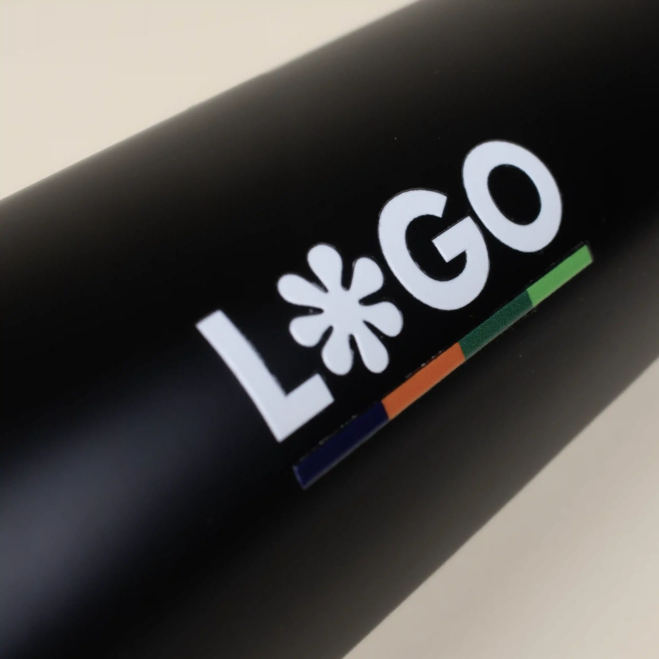 Botella térmica color negro personalizada con logo blanco fondo beige