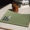 Mesa con cuaderno verde reciclado personalizado y vela