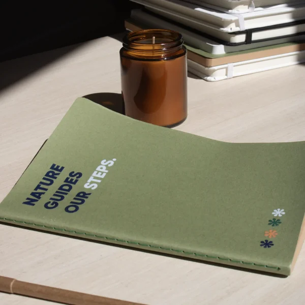 Mesa con cuaderno verde reciclado personalizado y vela