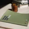 Mesa con cuaderno verde reciclado personalizado y vela