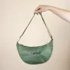 Riñonera verde personalizada con logo fondo beige modelo mano