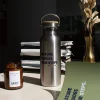 Mesa madera con botella de acero inoxidable cuaderno verde y vela