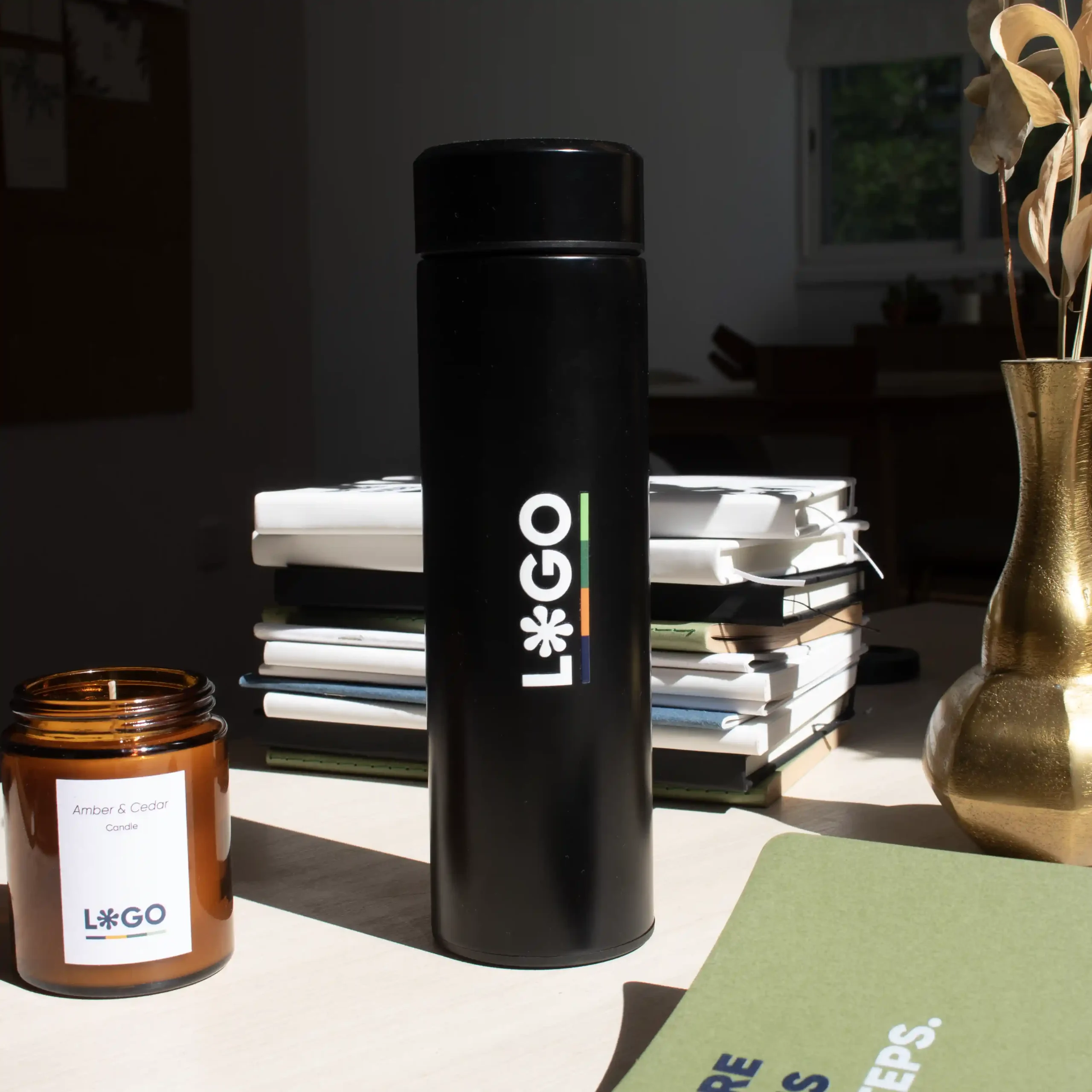 Mesa con termo acero inoxidable personalizado negro logo blanco vela y cuaderno verde