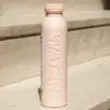 Botella rosa de caña de azúcar personalizada apoyada en una escalera de la calle