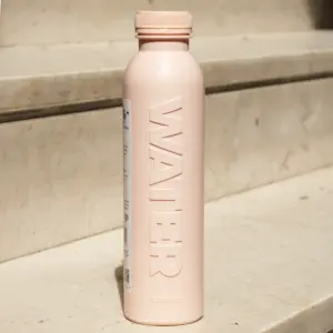 Botella rosa de caña de azúcar personalizada apoyada en una escalera de la calle