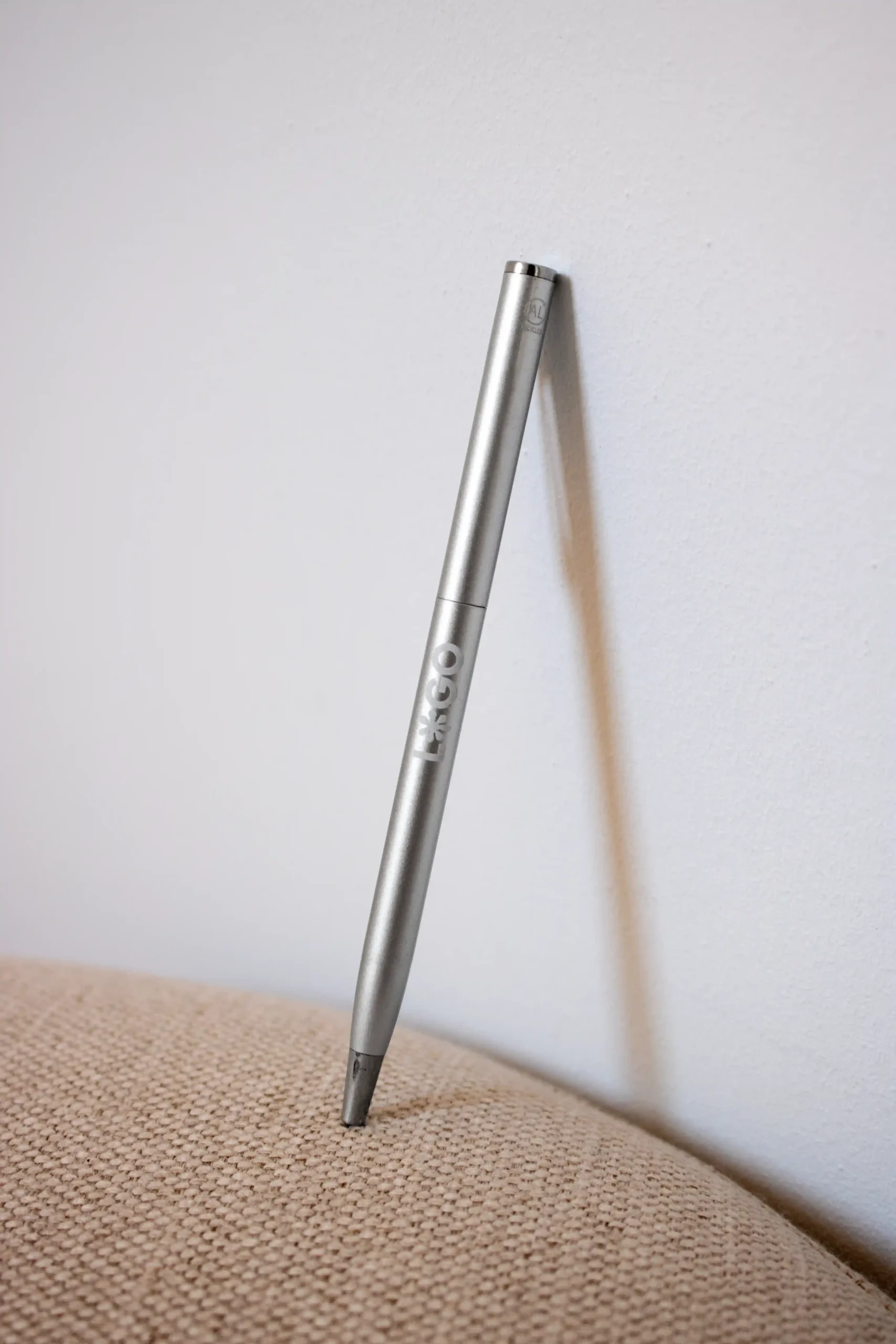 Personalised aluminum pen with logo leaning against the wall