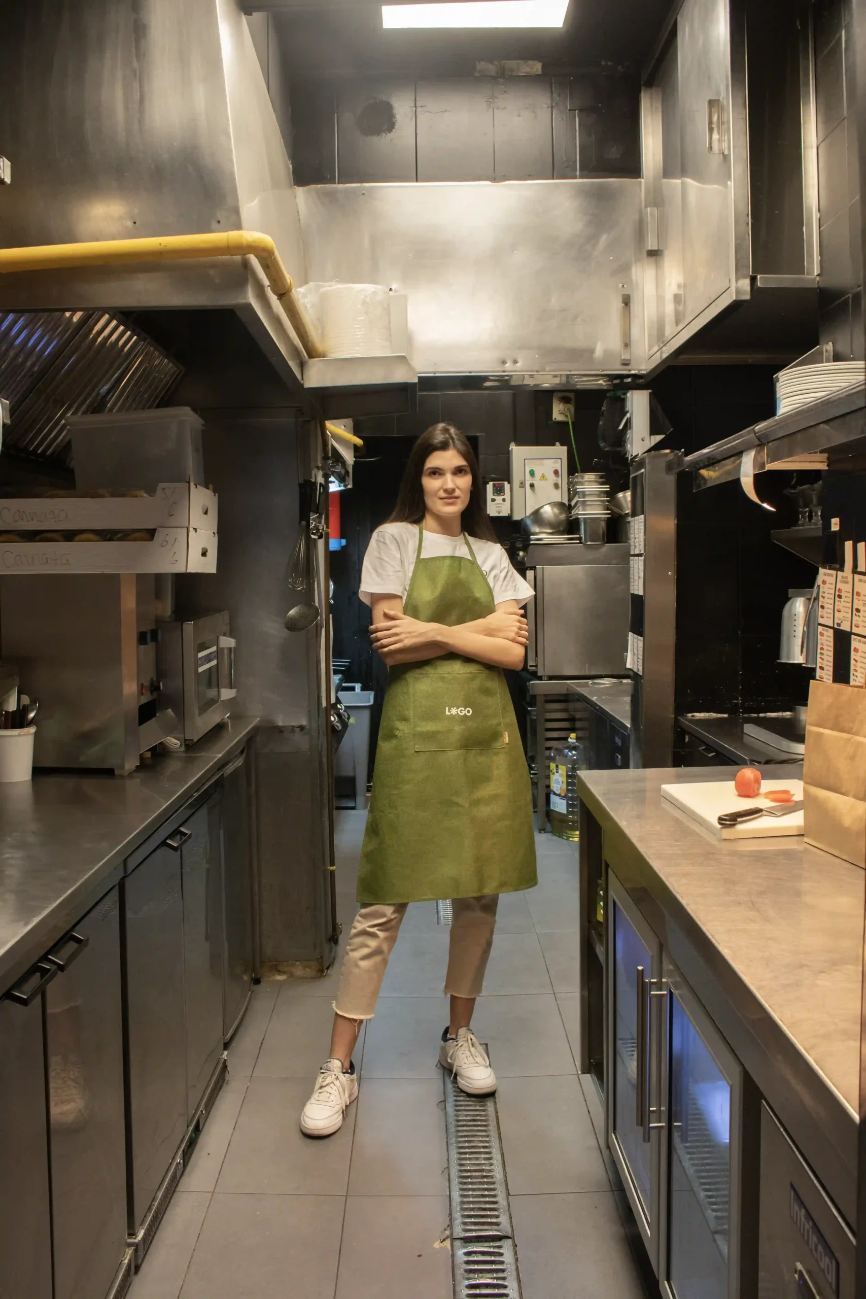 Tablier vert écologique modèle femme dans la cuisine d'un restaurant