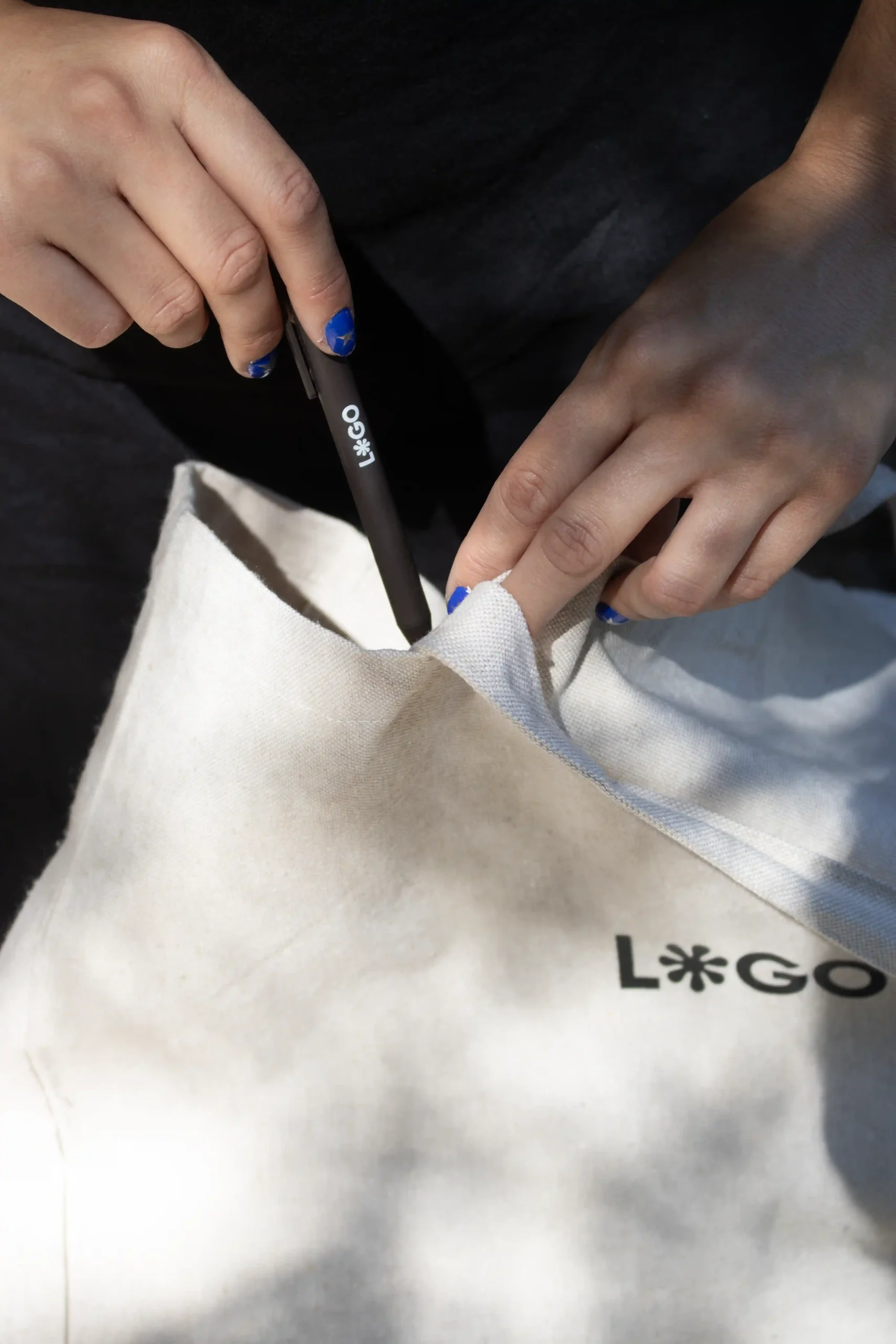 Hands placing a custom coffee pen into a cotton tote bag