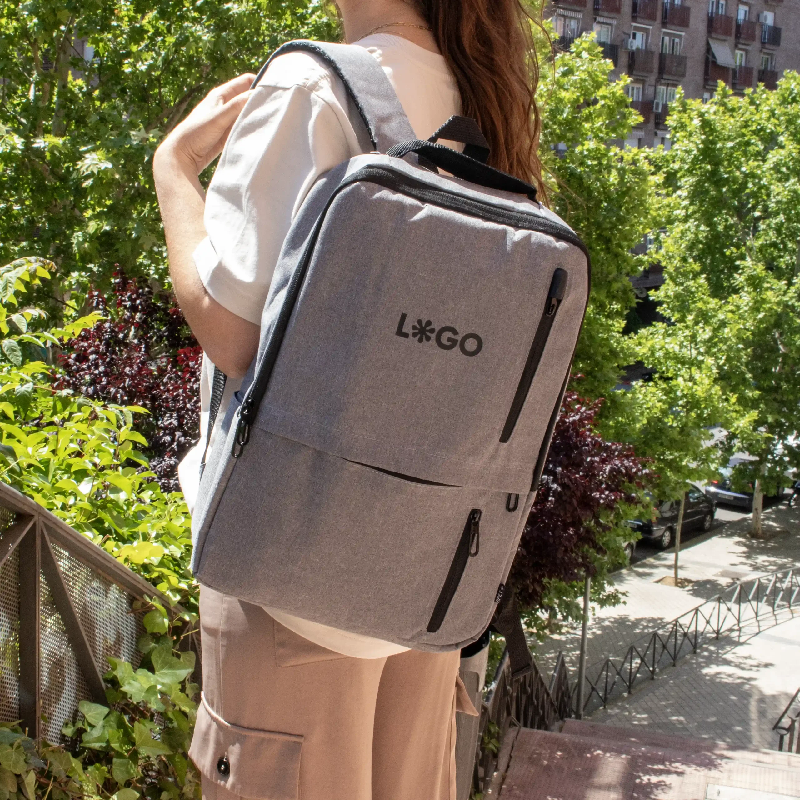 Mochila de empresa personalizada gris con logo negro modelo chica en la calle