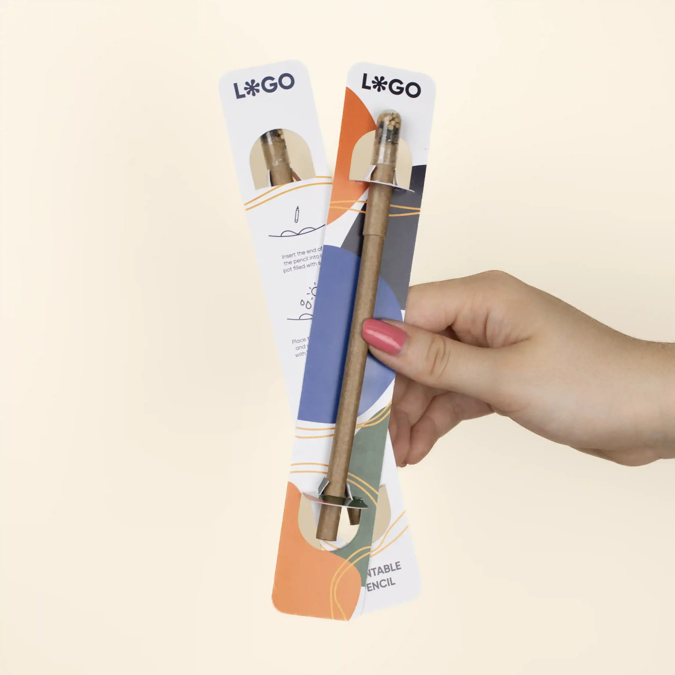 Hand holding two plantable pens on a personalised white cardboard holder