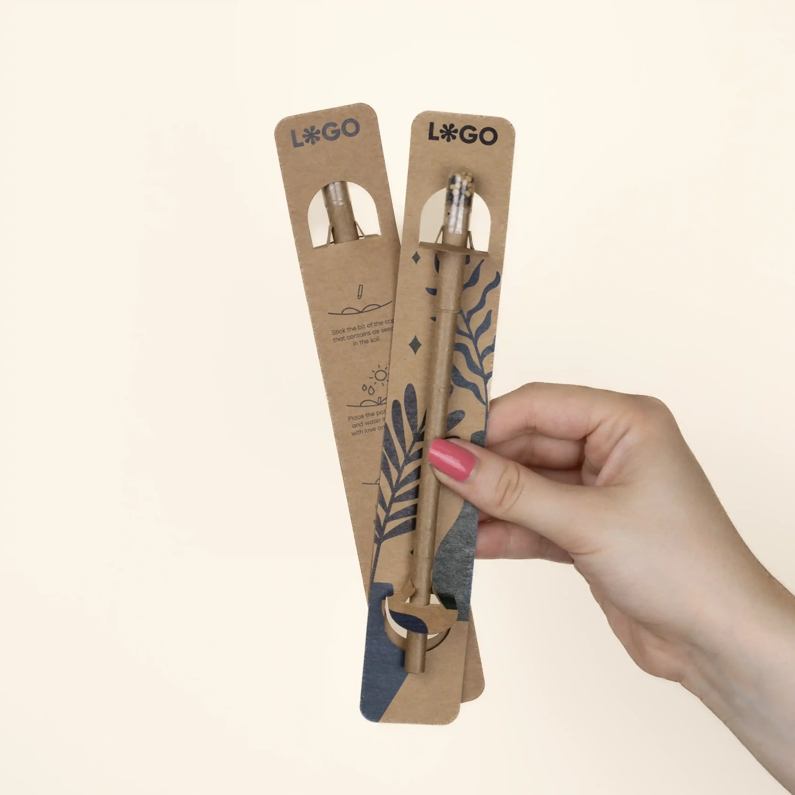 Hand holding two plantable pens on a personalised kraft cardboard holder
