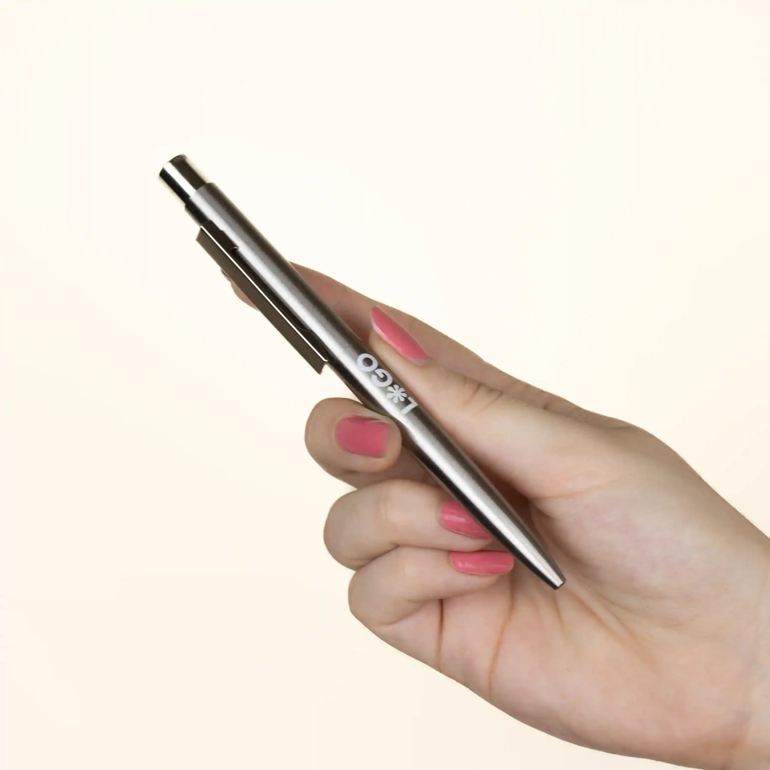 Hand holding a personalised stainless steel pen on a beige background