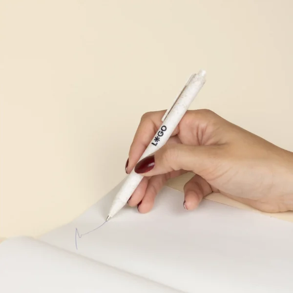 Mano sujetando bolígrafo de caña de trigo blanco personalizado con logo