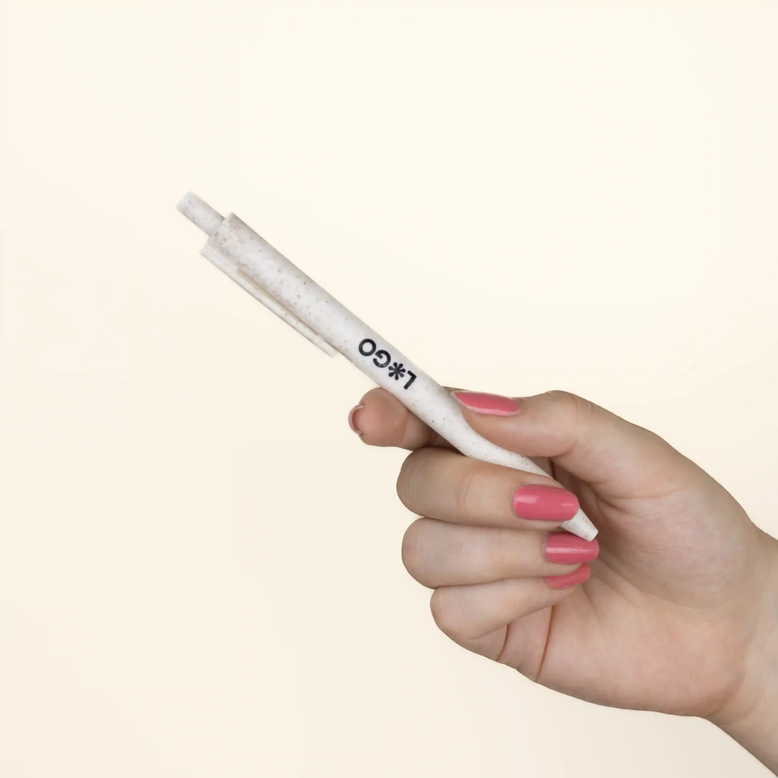 A hand holding a personalised white wheat pen, custom-made with a logo