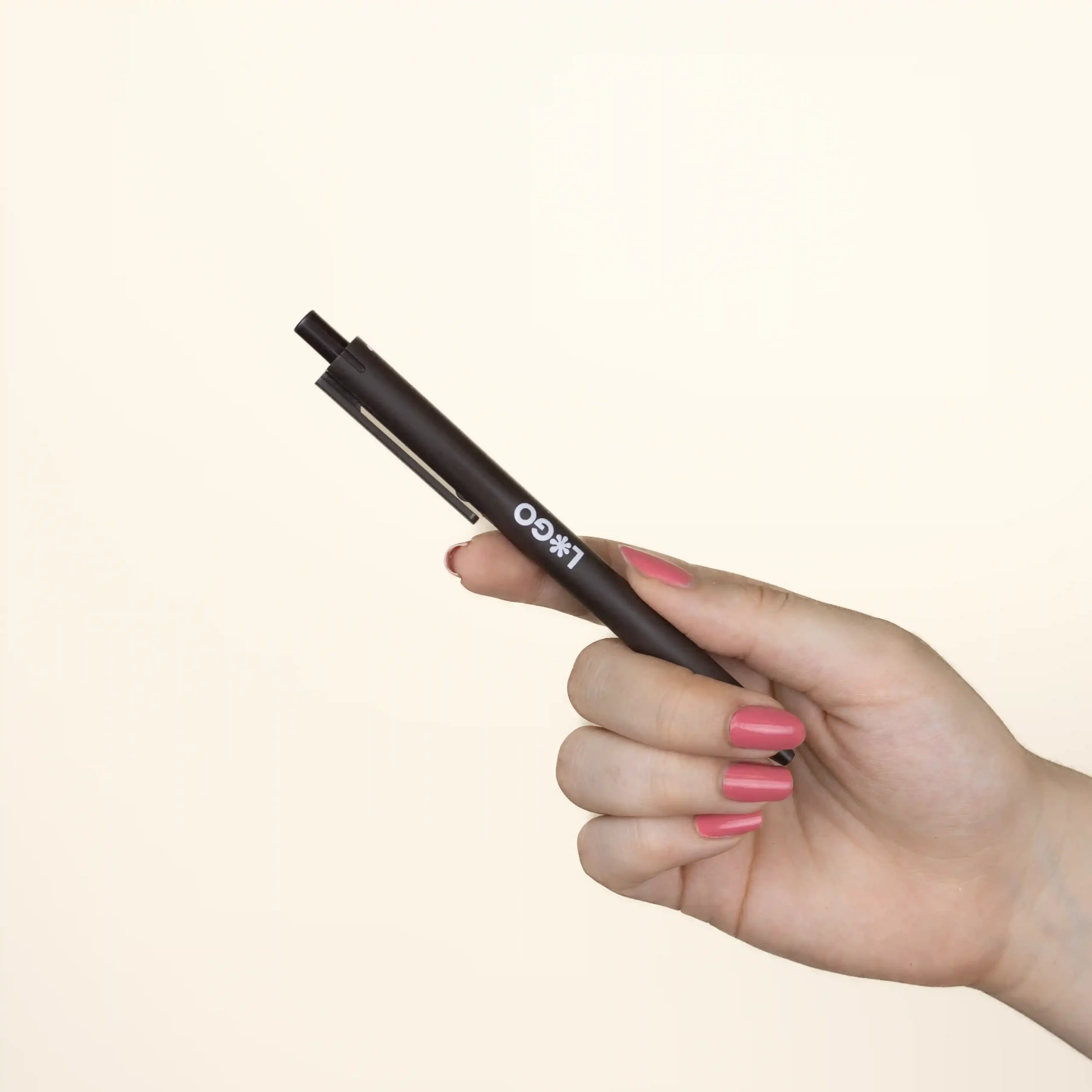 A hand is holding a custom coffee pen with a white logo