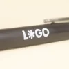 Cuerpo de bolígrafo marrón de fibra de cafe personalizado con logo blanco sobre fondo beige