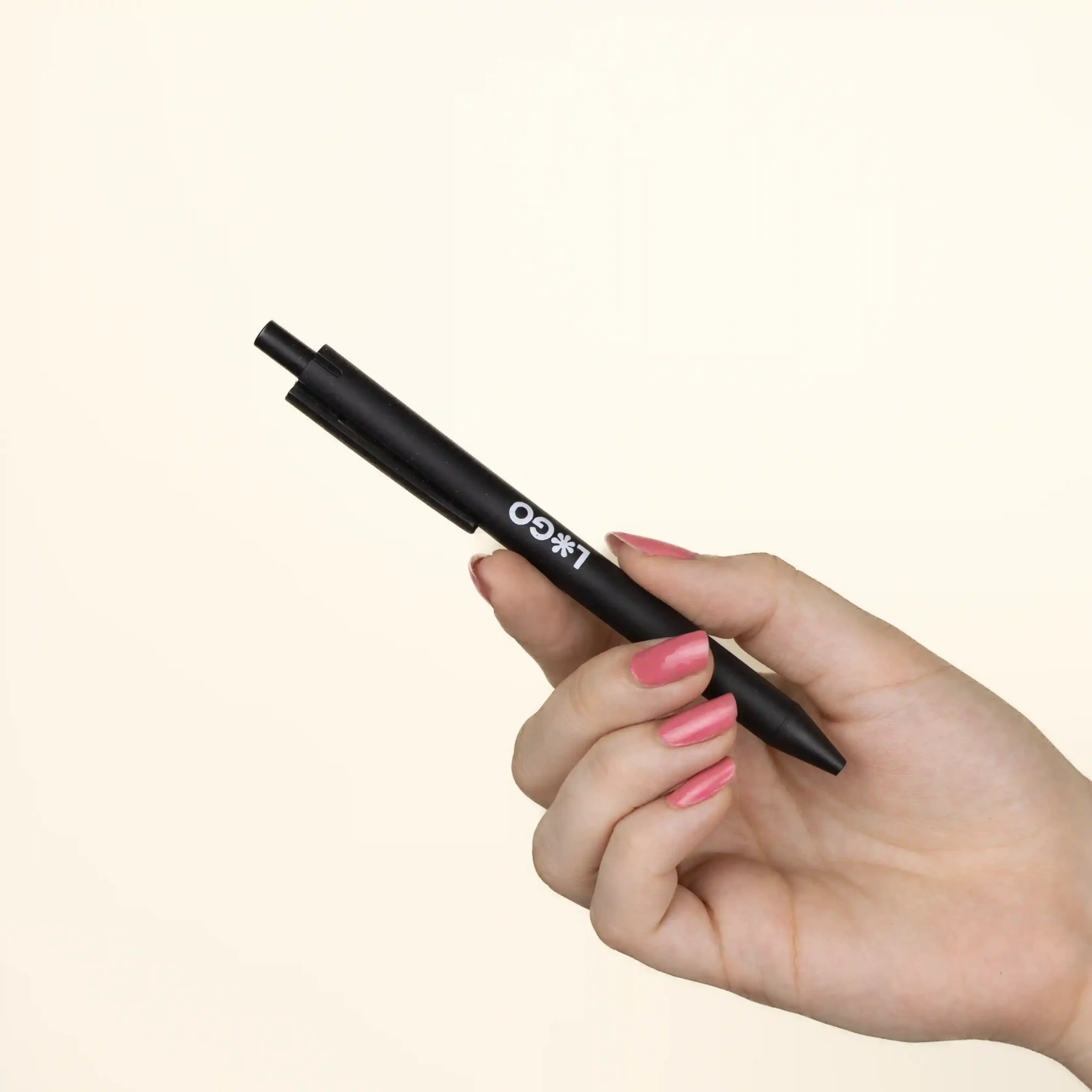 A hand holding a personalised black wheat pen, custom-made with a logo
