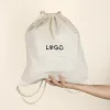Mochila cuerdas personalizada tipo saco color beige con logo negro modelo mano fondo beige