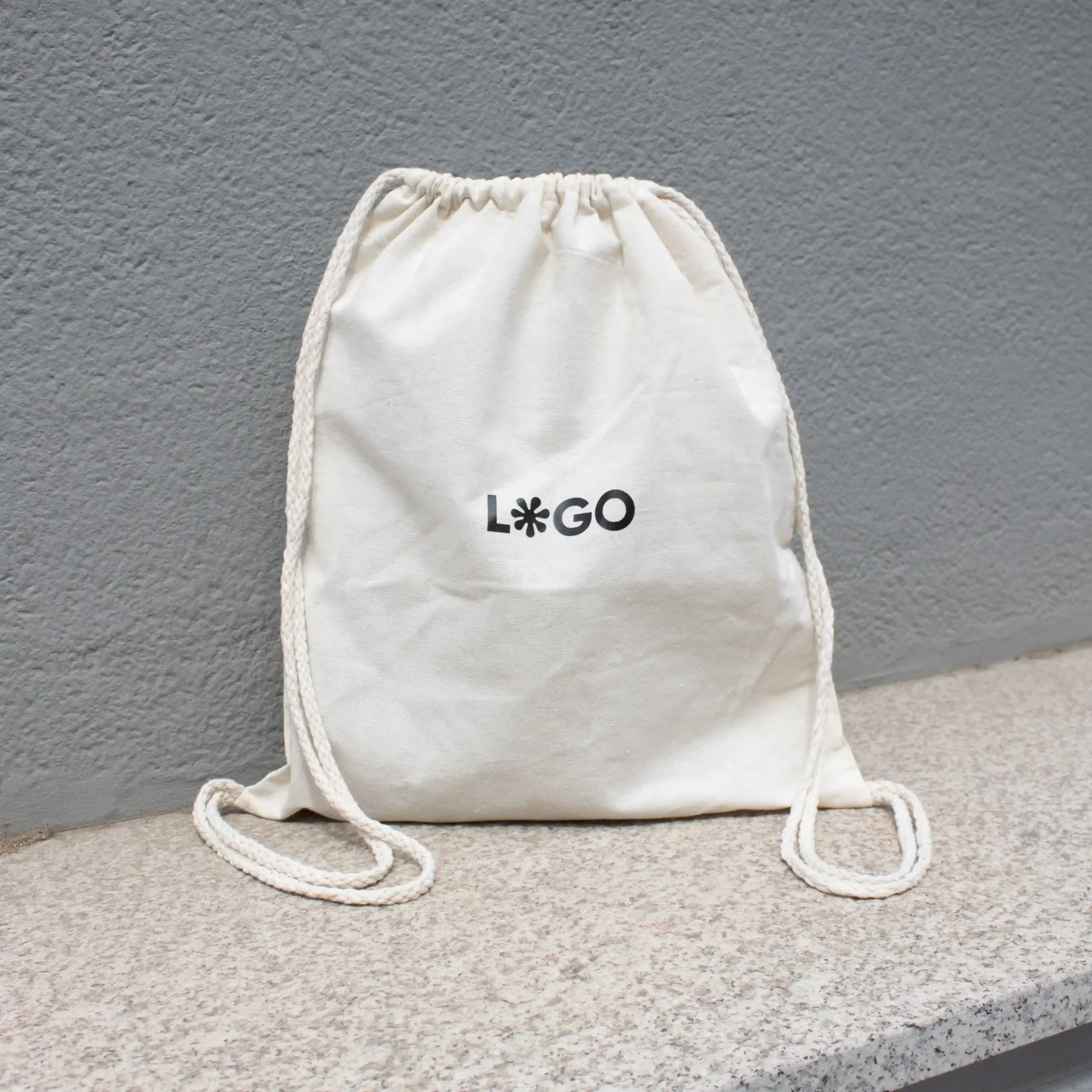 Mochila cuerdas personalizada LACCI Sol Mochila cuerdas personalizada tipo saco color beige con logo negro fondo gris