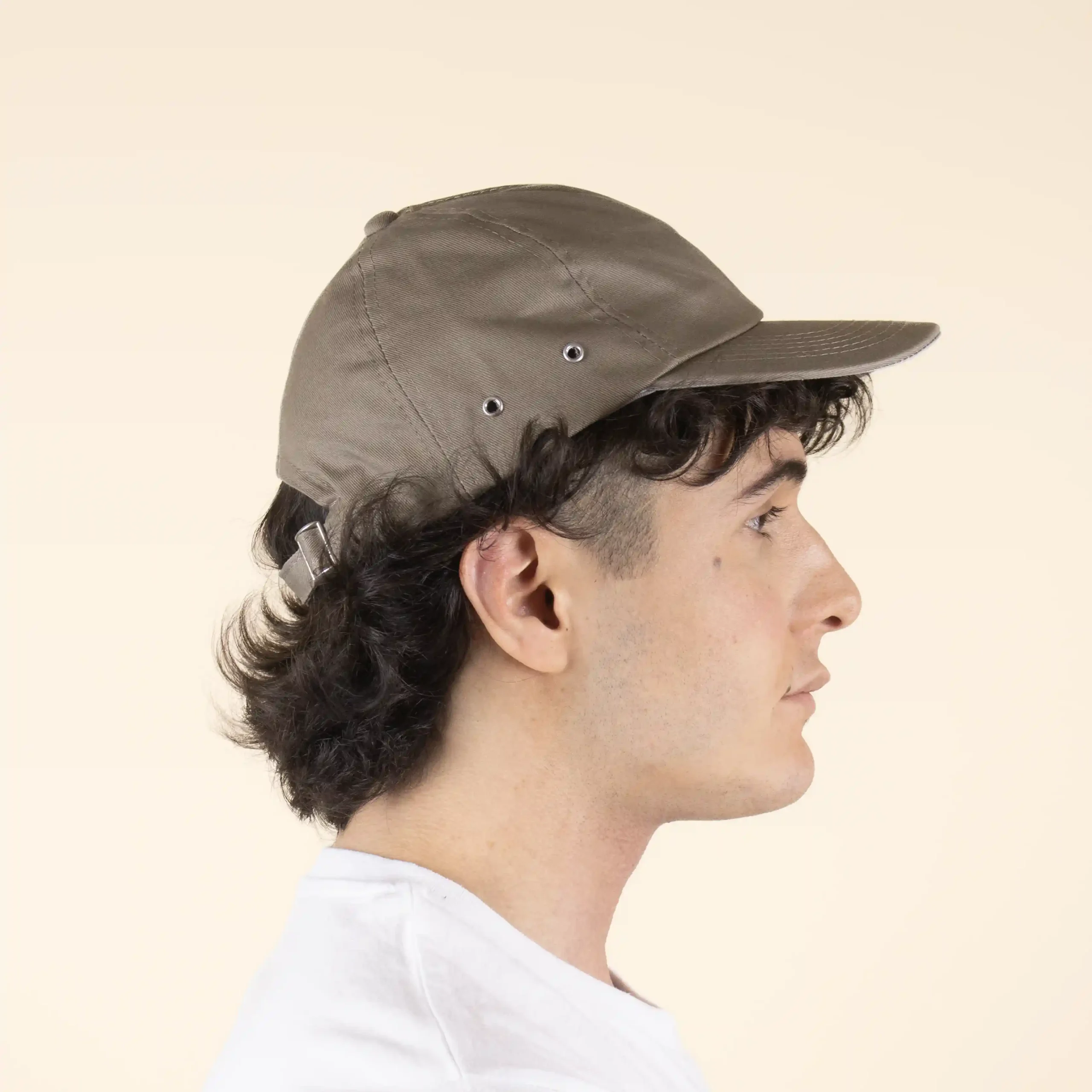 Casquette brune personnalisée modèle homme en position latérale sur fond beige.