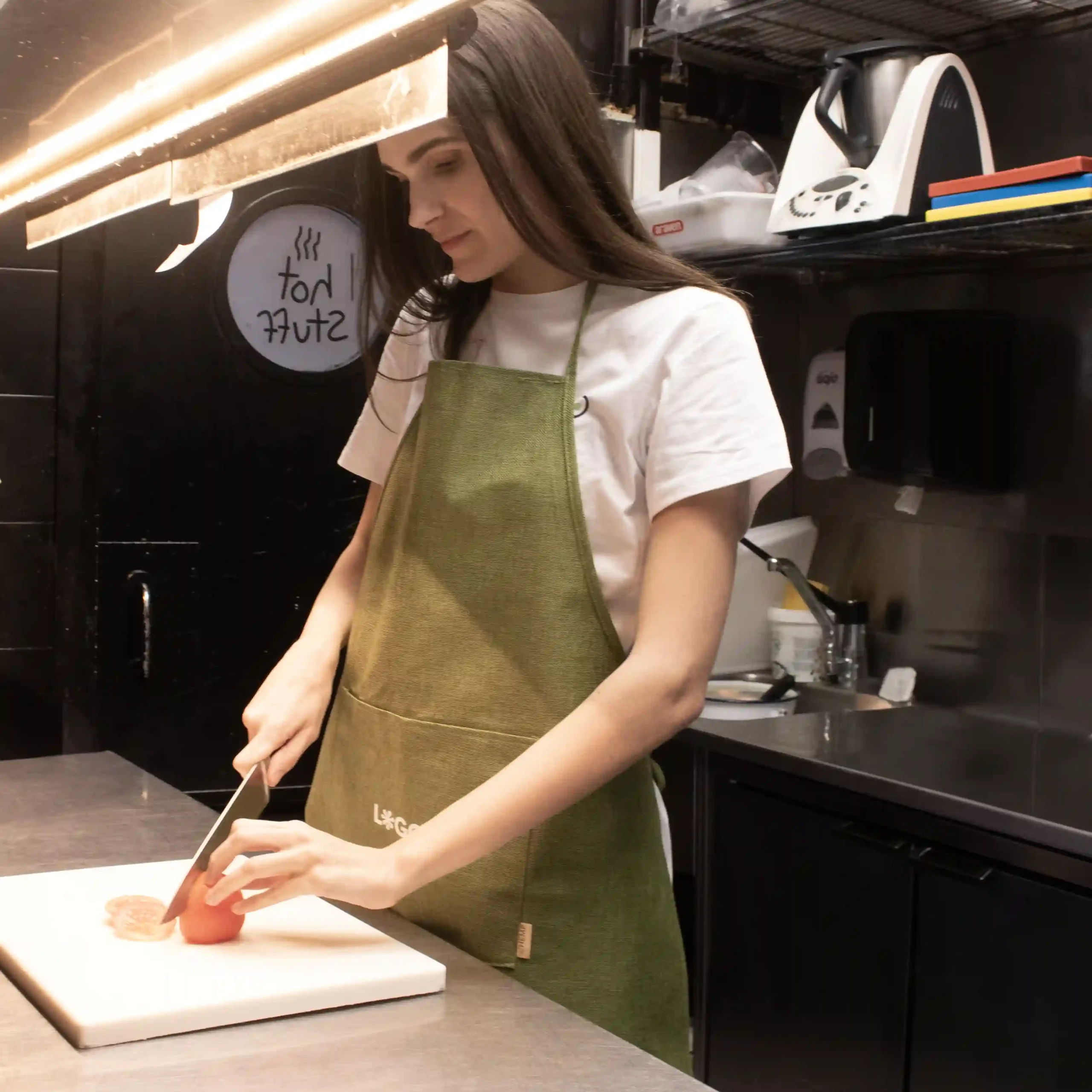 Delantal ecológico OSCAR Verde Lifestyle Delantal ecológico verde modelo chica en cocina de restaurante