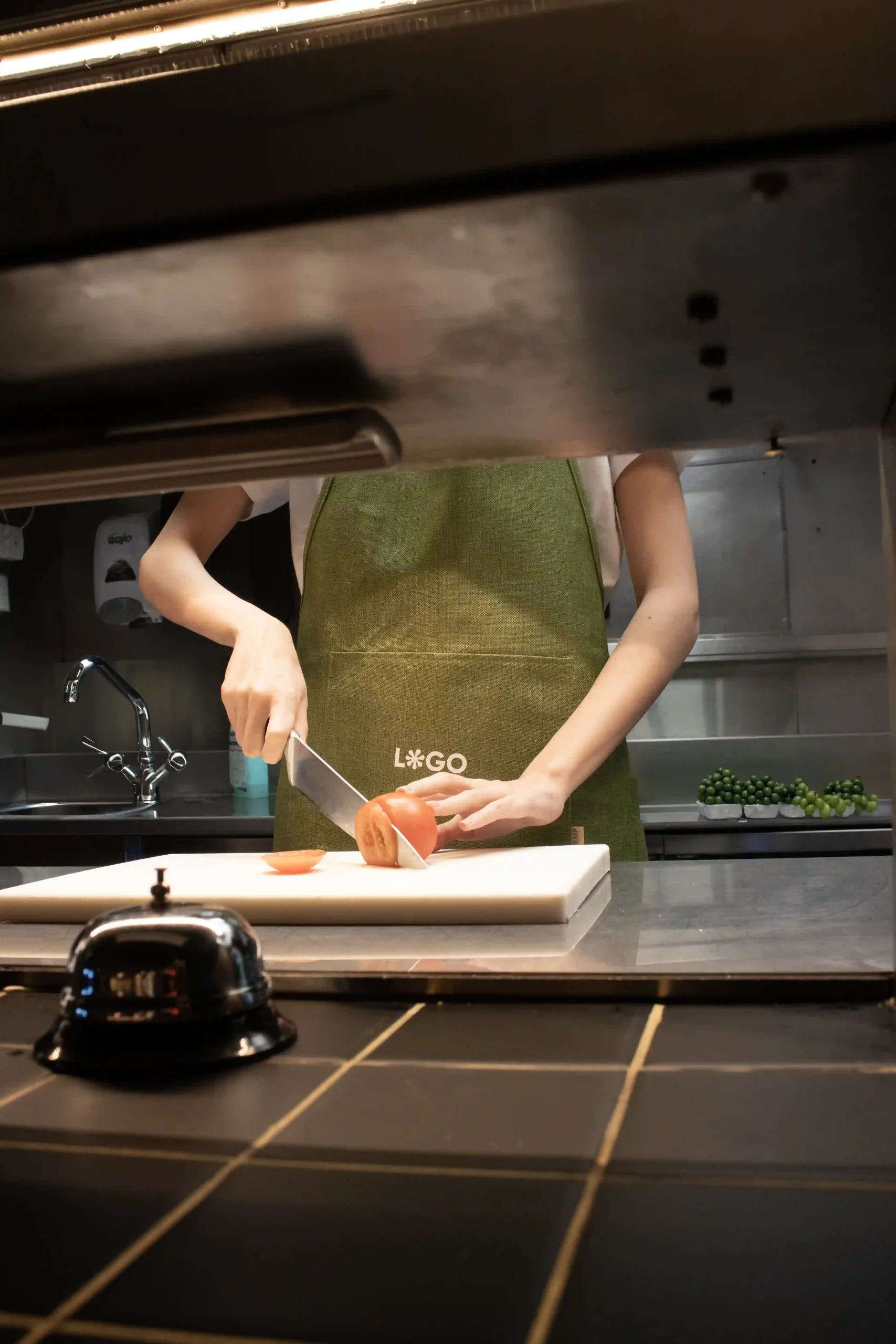Tablier vert écologique modèle femme dans la cuisine d'un restaurant