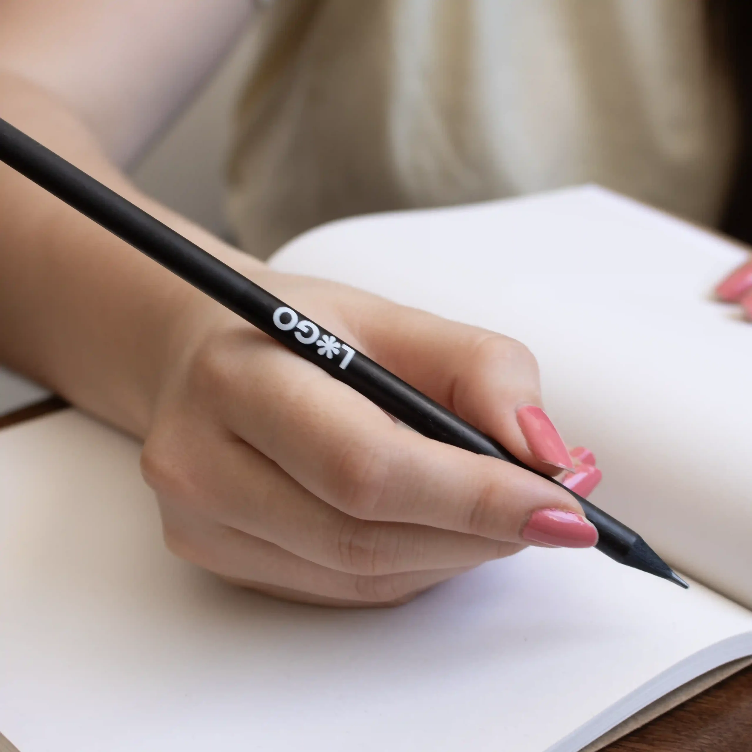 Promotional wooden pencil BRUNO Hand writing in a notebook with a personalised black wooden pencil with a white logo