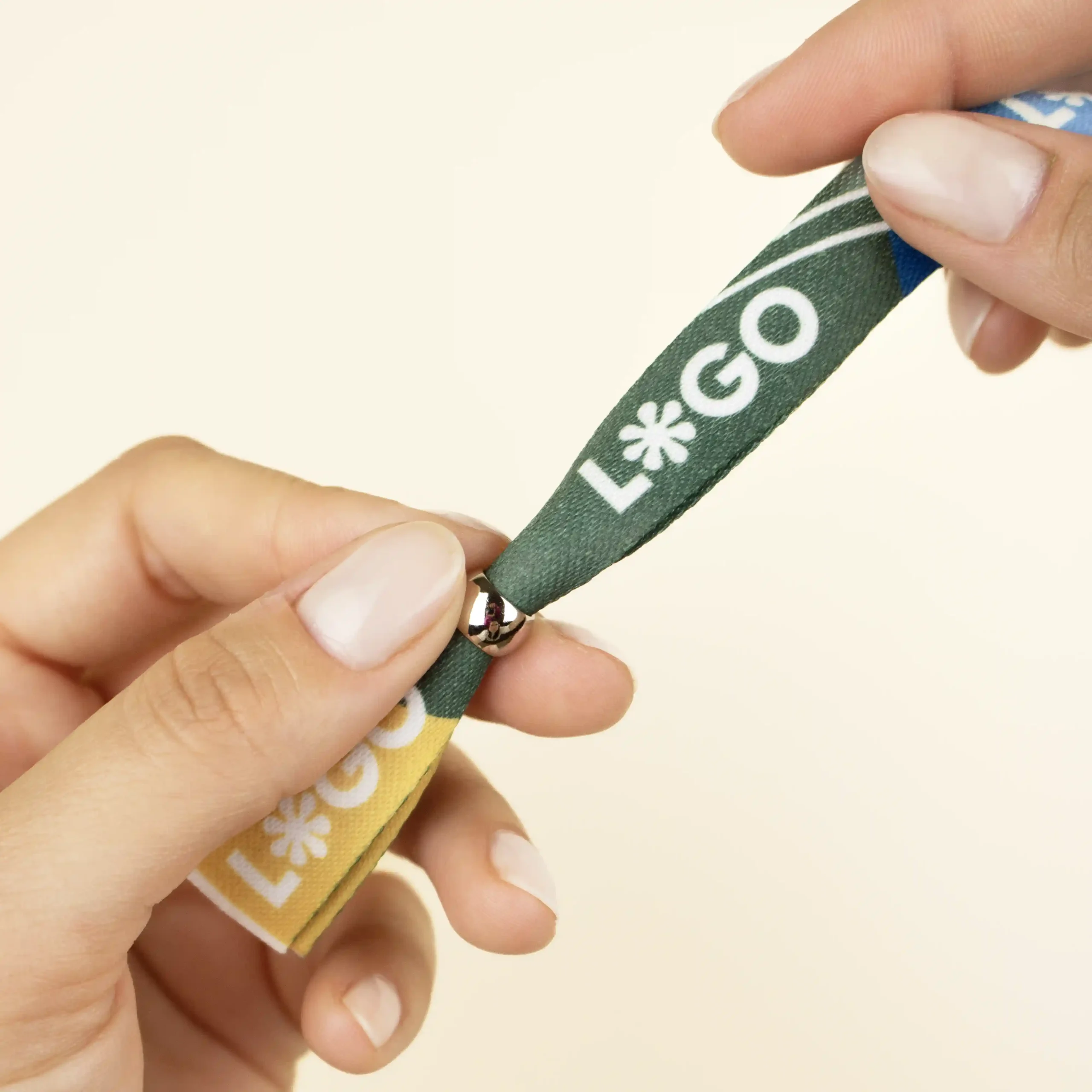 Manos sobre fondo beige mostrando una pulsera reciclada en rPET personalizada con logo a todo color