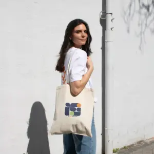 Chica paseando en la calle llevando una bolsa de algodón personalizada con logo de colores