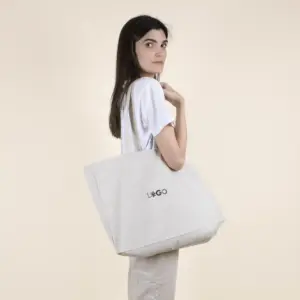 Chica sobre fondo beige con bolsa de algodón reciclado personalizada con logo