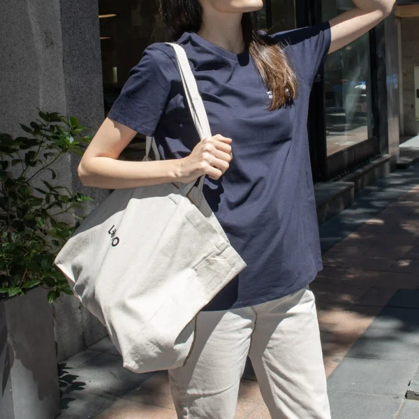 Chica con camiseta azul caminando por la calle con bolsa de algodón reciclado