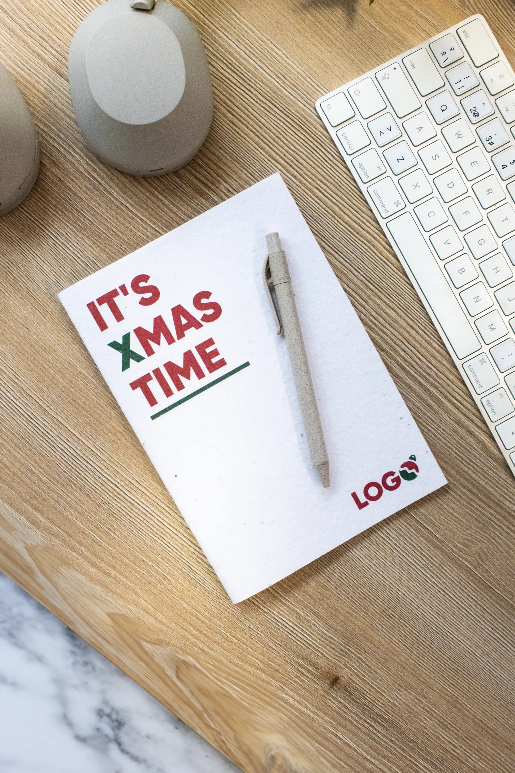 Cuaderno SHON Pack IT'S CHRISTMAS TIME Cuaderno plantable personalizado con diseño de Navidad sobre una mesa de madera de trabajo con un bolígrafo y un teclado de ordenador