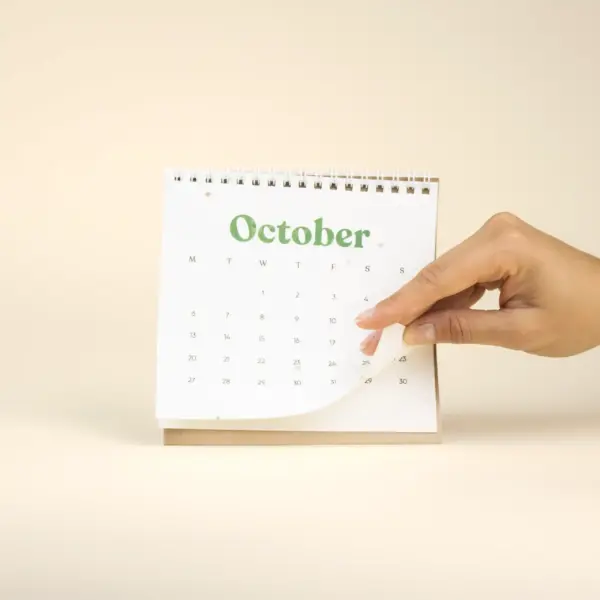Mano pasando la hoja de octubre de una calendario plantable de mesa