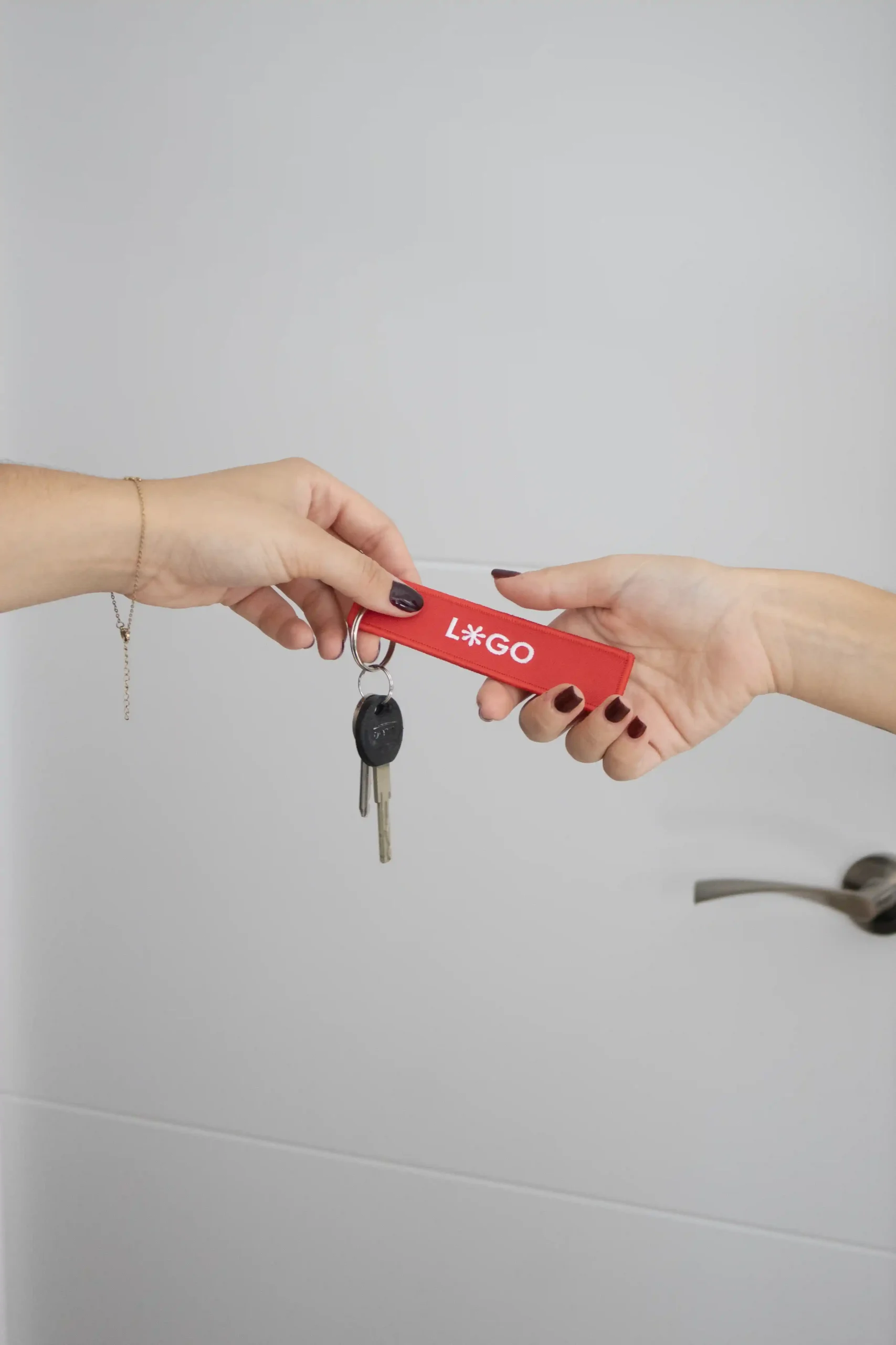 Manos sujetando unas llaves con llavero de tela rojo personalizado bordado con hilo blanco