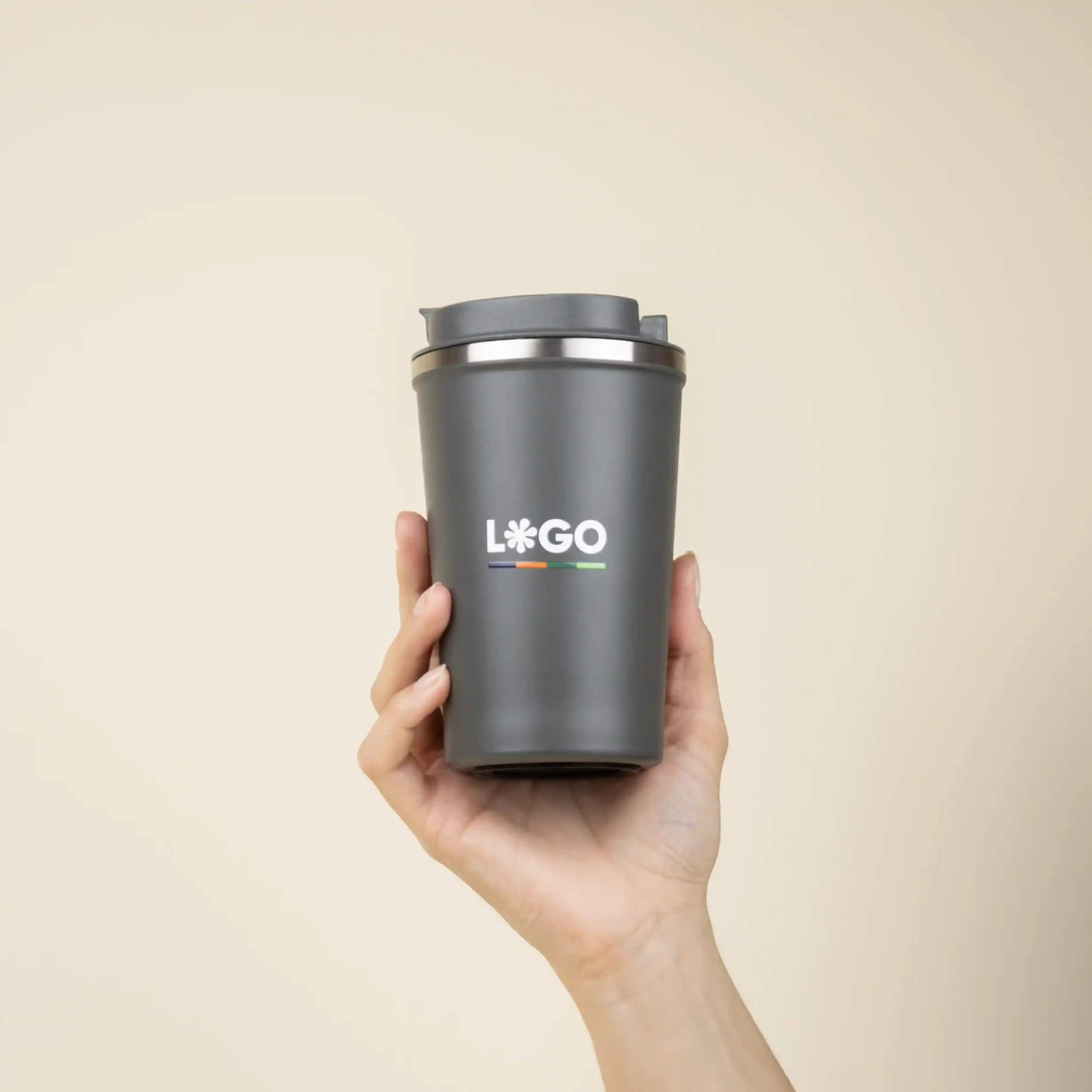 Mano cogiendo una taza térmica gris personalizada con logo blanco