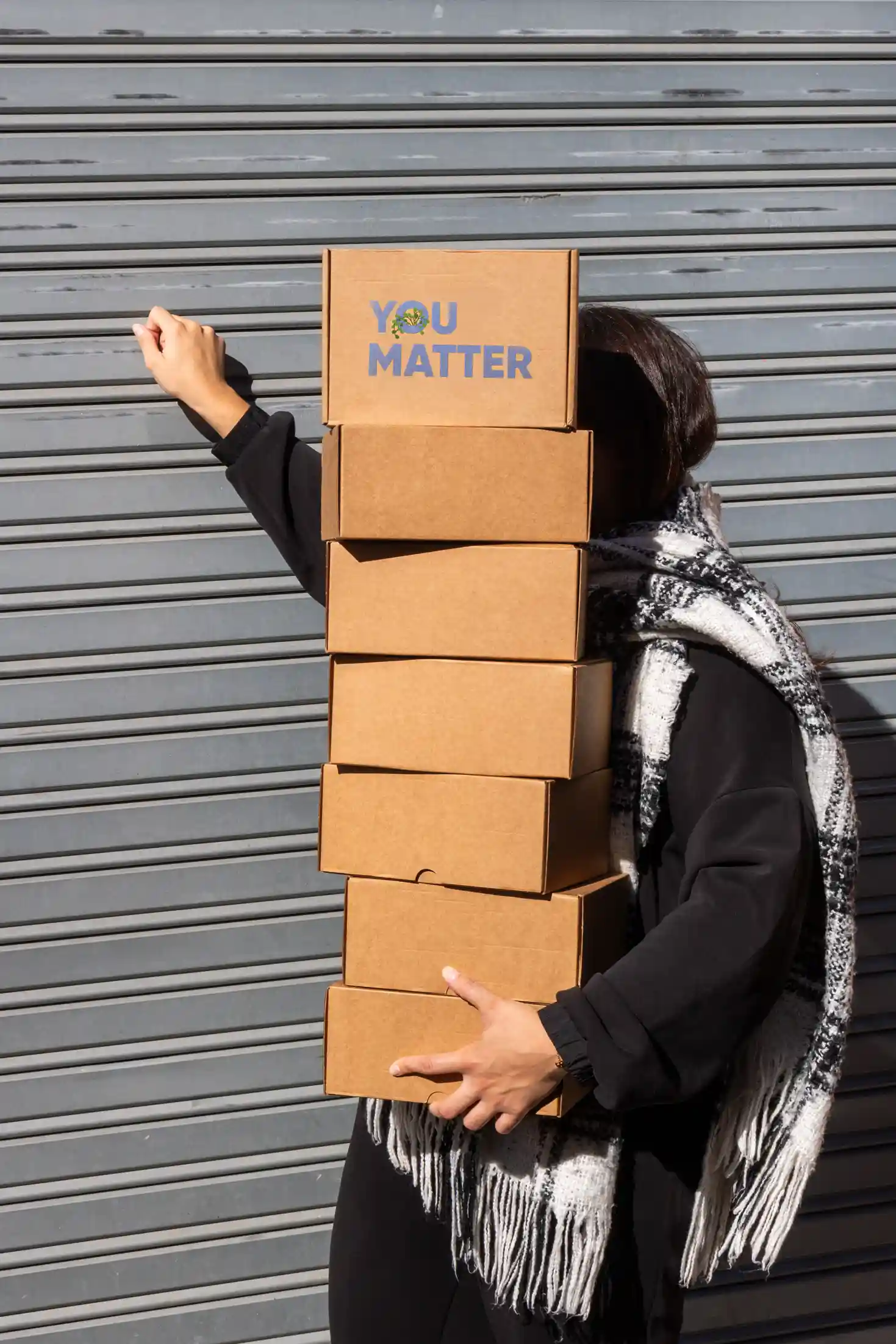 Chica cargando cajas de cartón personalizadas para welcome packs de empresa